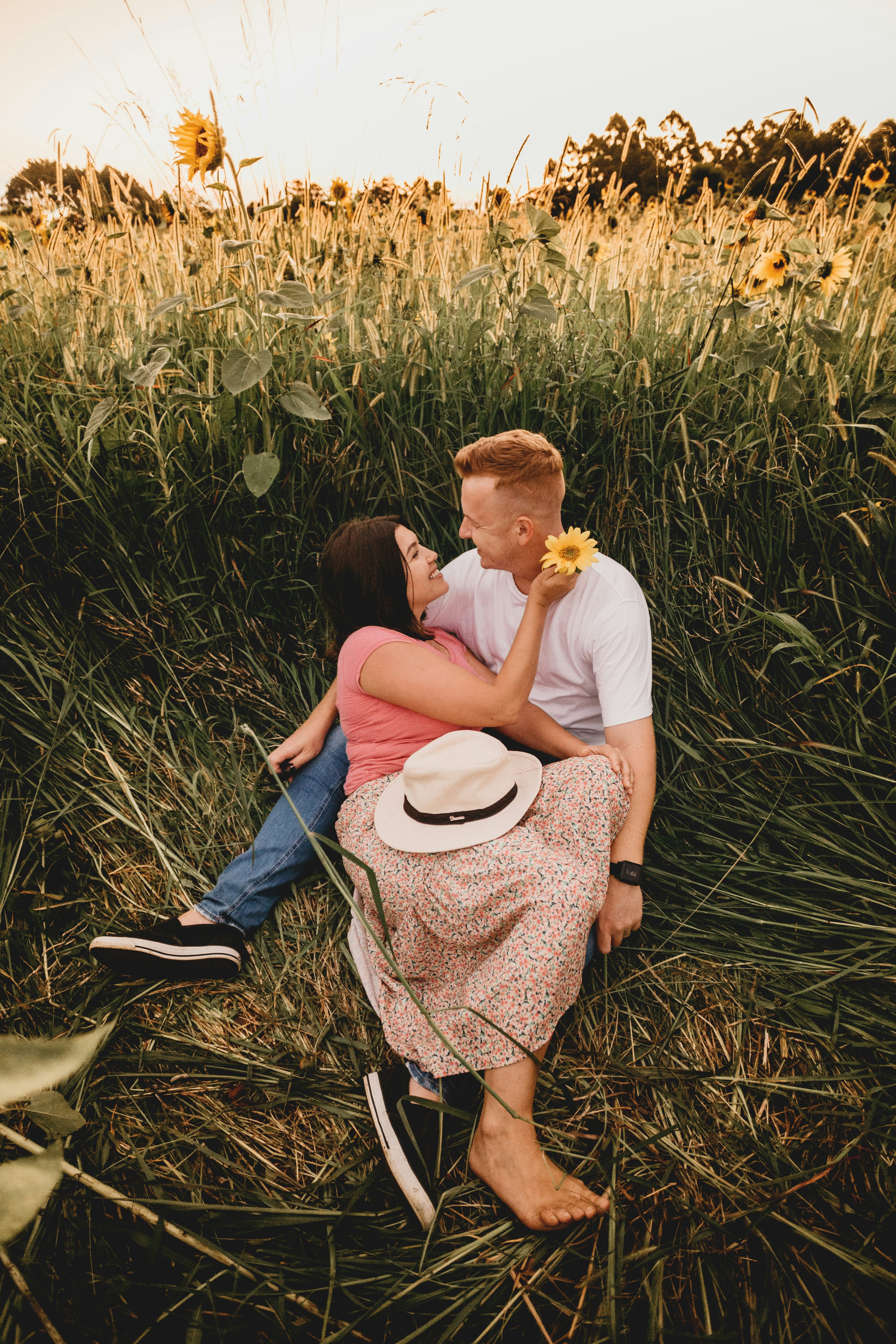 man in white shirt carrying woman in brown and white dress on green grass field during